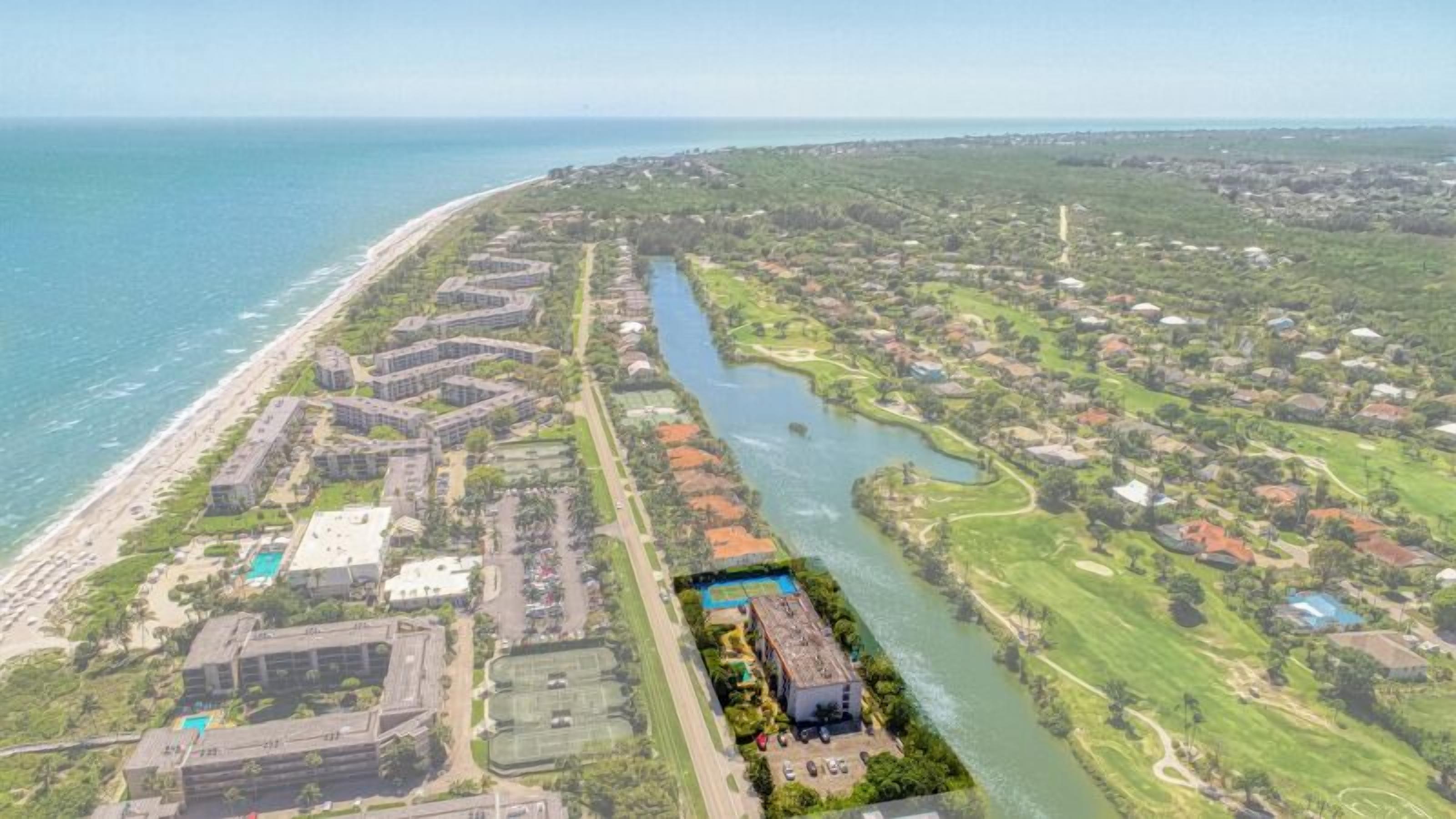 Vue aérienne d’une station balnéaire avec des villas en bord de mer, une rivière qui traverse le domaine et un terrain de golf.