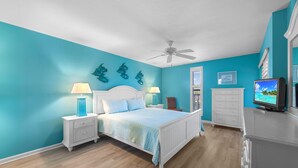 A bedroom with a bed, nightstands, a dresser, a television, and decorative wall art.