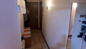 A narrow hallway with a tiled floor, a door at the end, and a mirror on the right wall. - 100m from ski slopes, 6th floor, balcony, tv, ski locker, 61m², Val Thorens (Val Thorens)