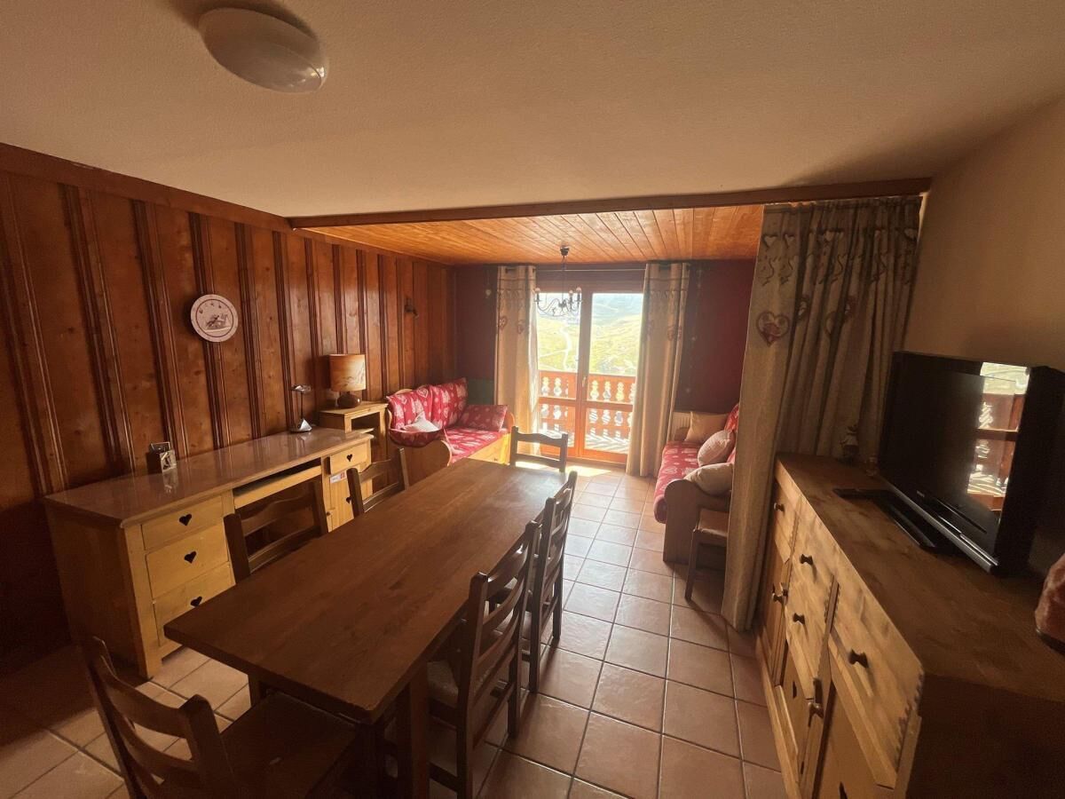 A cozy kitchen with wooden cabinets, a dining table, and a TV.