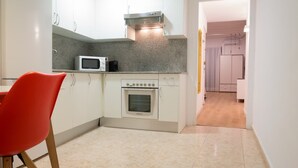 Una cocina pequeña con armarios blancos, un microondas y un horno.
