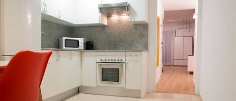 A compact kitchen with white cabinets, a microwave, and an oven.