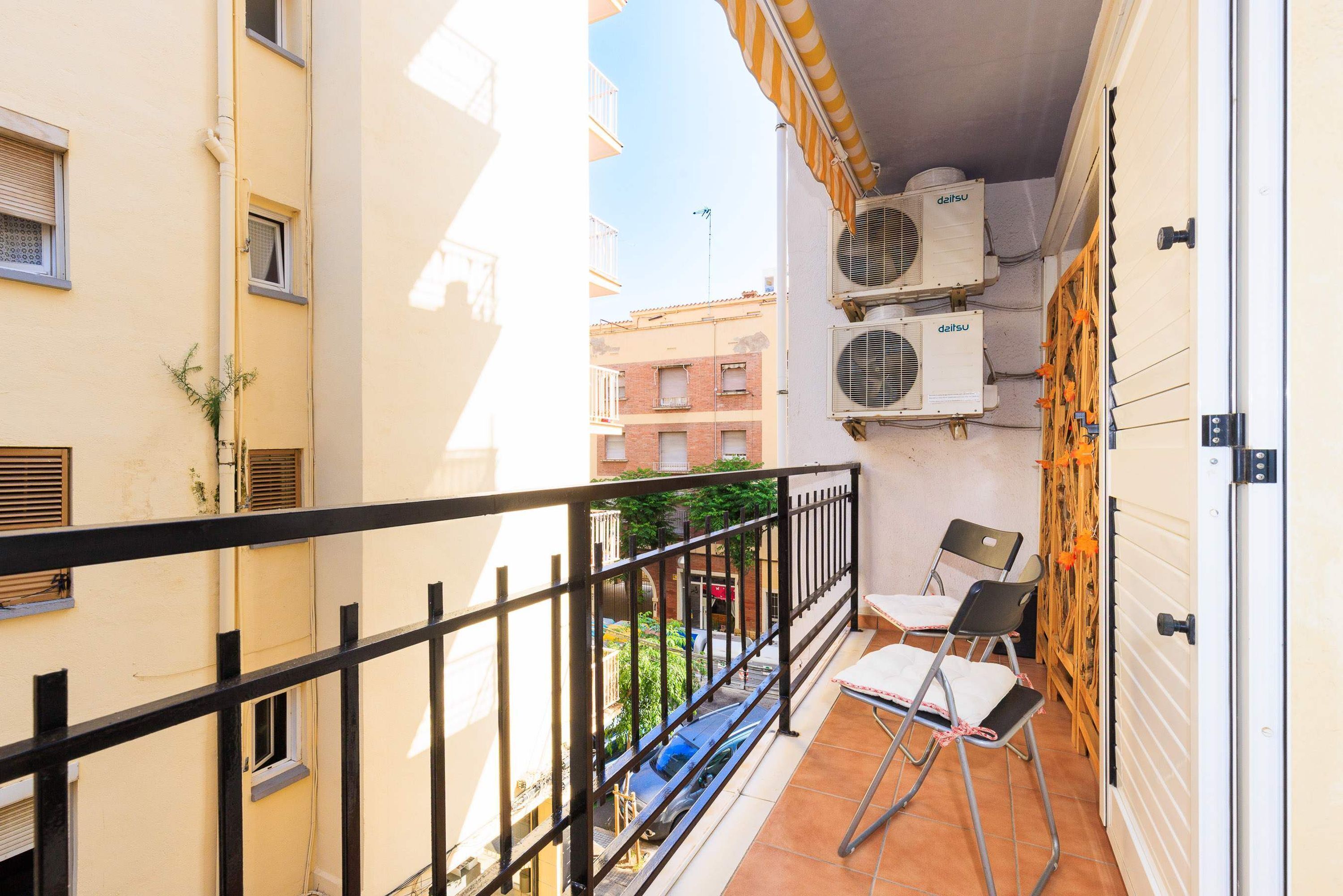 A balcony with air conditioning units, a chair, and a table.
