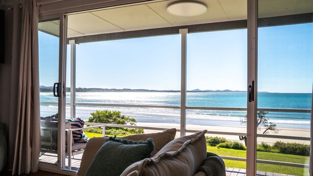Una habitación con puerta de vidrio corrediza que da a un balcón con vista a la playa y al océano.