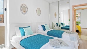 Une chambre moderne avec deux lits, des murs blancs et un grand miroir.