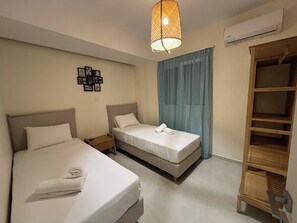 Ein Hotelzimmer mit zwei Betten, einem Holzschrank, einer Wand-Klimaanlage und einer Pendelleuchte.