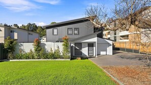 A modern two-story house with a garage, a well-maintained lawn, and a wooden fence.