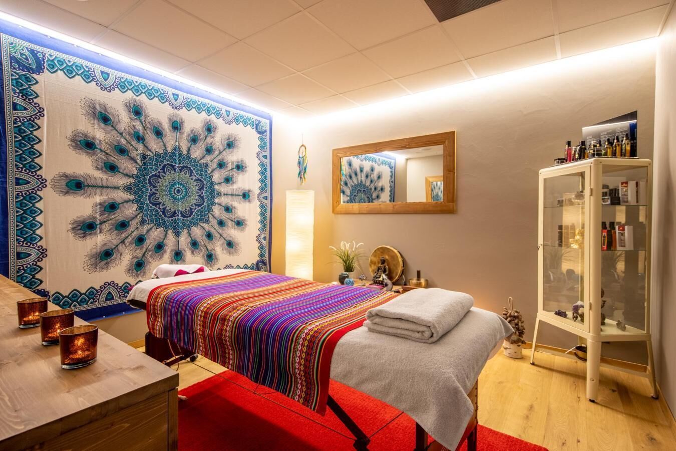 A room with a bed, a mirror, a cabinet, and a tapestry.