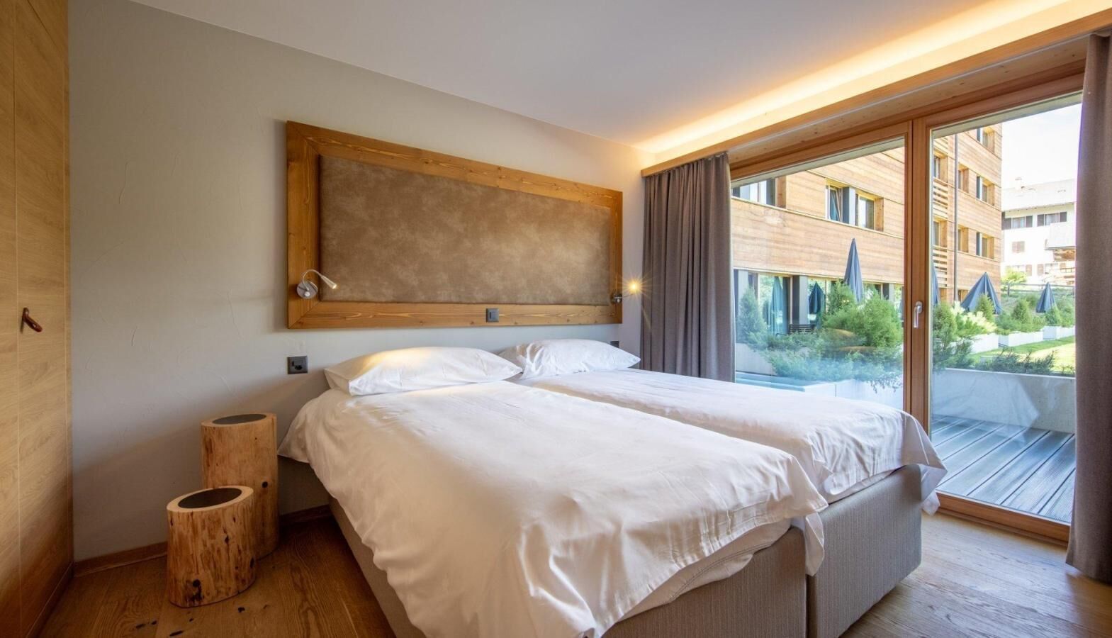 Een moderne hotelkamer met een groot bed, houten details en uitzicht buiten.