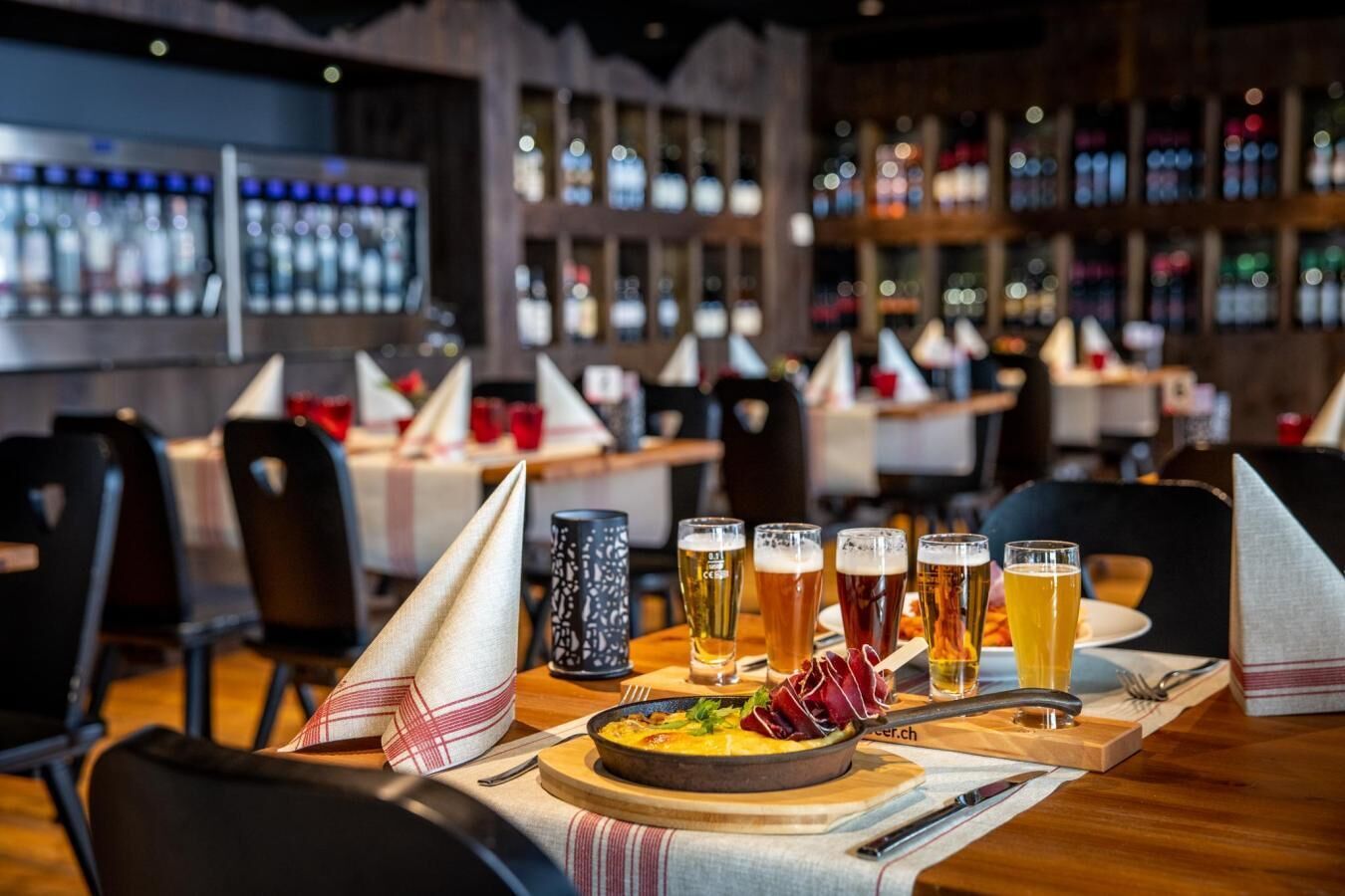 Un ambiente de restaurante con varias mesas, cada una con un juego de vasos y un bol de comida.