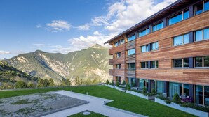 A modern building with a flat roof, large windows, and a courtyard with a lawn and seating area. - Wifi, ski-in/ski-out & foot of the slopes, fitness, sauna, hammam, tv, ski locker, 55m², Vercorin (Vercorin)