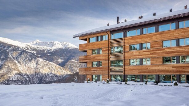 A modern multi-story building with large windows, set against a snowy mountain backdrop. - Wifi, 250m from shops, fitness, sauna, hammam, tv, ski locker, 67m², Vercorin (Vercorin)