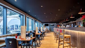 A modern restaurant with wooden flooring, black chairs, and a bar area with stools. - Wifi, 250m from shops, fitness, sauna, hammam, tv, ski locker, 67m², Vercorin (Vercorin)