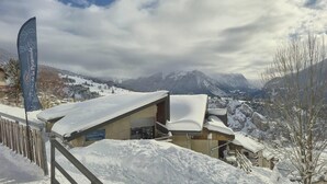 A snow-covered mountain resort with buildings, a flag, and a view of the mountains. - 150m from resort center, Ground floor, terrace, 27m², Aussois (Aussois)