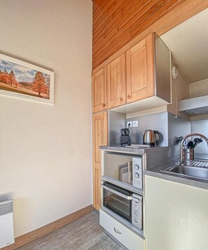 Une cuisine compacte avec des meubles de rangement en bois, un four encastré et un évier.