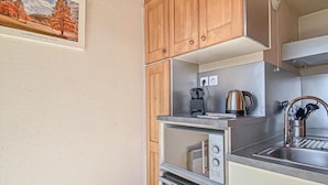 Une cuisine compacte avec des meubles en bois, un évier en acier inoxydable, une bouilloire et un four.