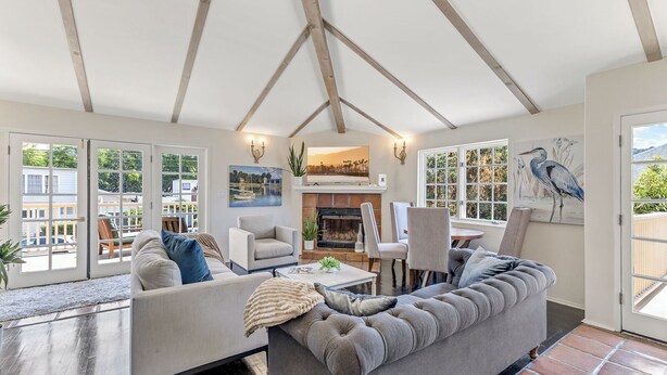 A spacious living room with a high ceiling, a fireplace, and large windows offering views of the outside.