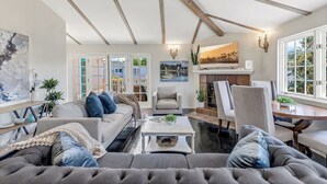 A spacious living room with a large grey sofa, a dining area with a wooden table, and a fireplace.