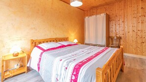 A wooden-paneled room with a bed, a nightstand, a lamp, and a hanging light fixture.