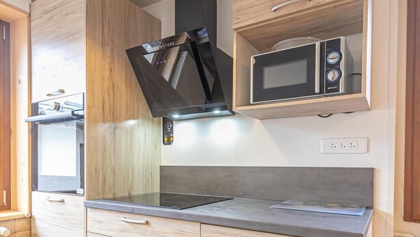 A modern kitchen with wooden cabinets, a built-in microwave, and a stainless steel stove.