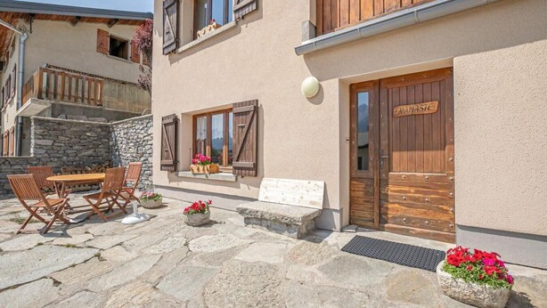 Une terrasse dallée de pierres, avec des meubles d’extérieur et des pots de fleurs.