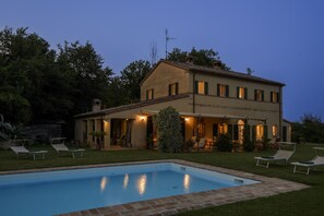 Une maison à deux étages avec une piscine, un espace salon extérieur et un jardin.