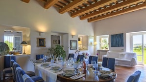 Comedor con una mesa redonda preparada para seis personas, rodeado de sillas tapizadas en azul.