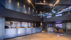 A modern hotel lobby with a reception desk, seating area, and a large screen displaying a landscape. - CICB HOSPITALITY (Brasilia)