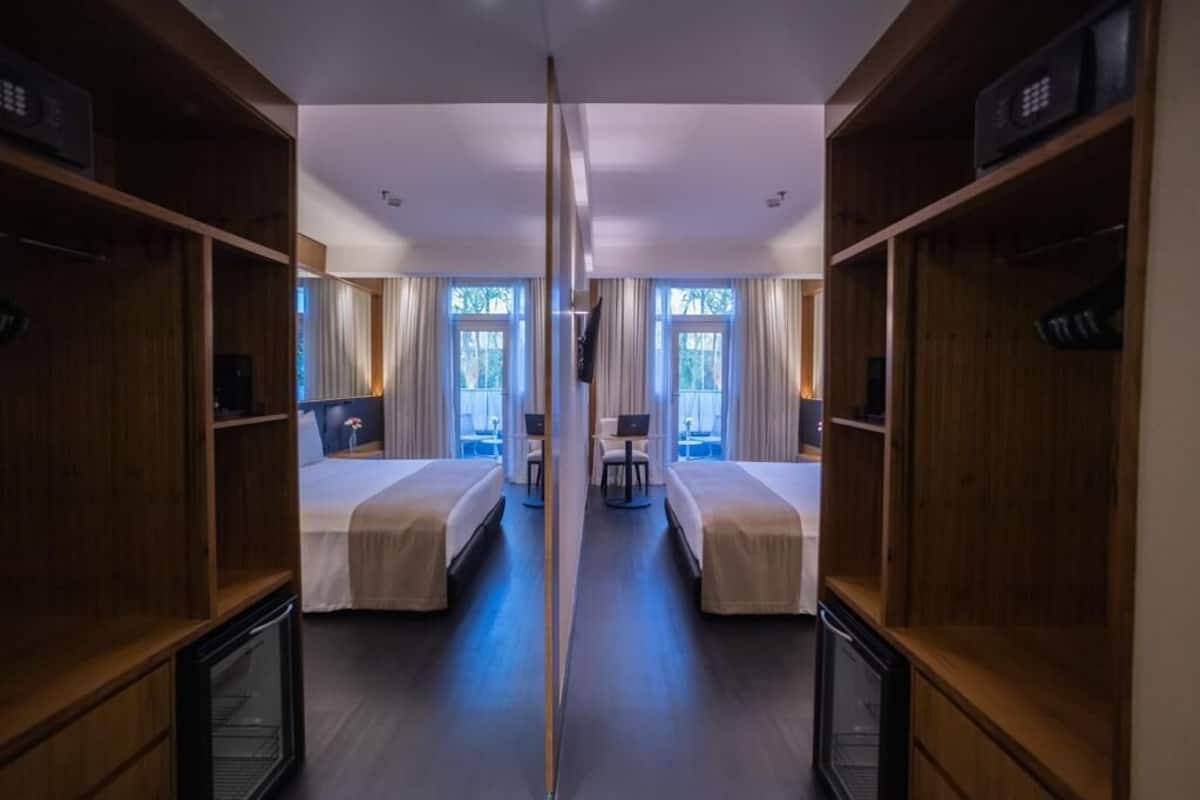 A hotel room with two beds, a desk, a chair, and a TV.