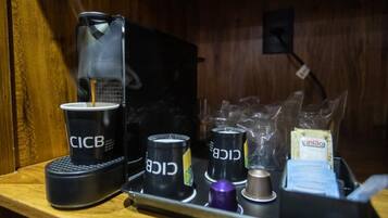 En kaffemaskine med engangskopper mærket 'CICB' og en bakke med plastikposer og en pakke 'união' te.