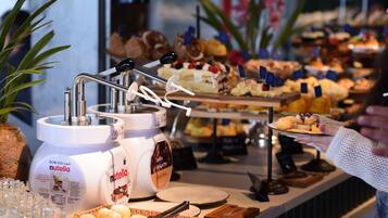 A buffet with various food items and two large containers of Nutella.
