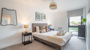 A modern bedroom with a large bed, bedside tables, a mirror, and a window with a view. - 42 City Gate - 24-hour Gym Access Included! Sleeps 4 guests in 2 bedrooms (York)