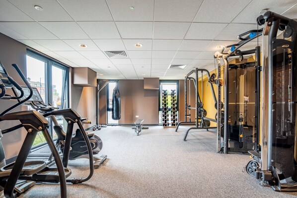 Une salle de sport équipée de tapis de course, d’un vélo d’appartement et de matériel de musculation.
