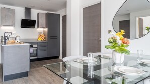 A modern kitchen with a central island, built-in appliances, and a dining area with a glass table and chairs. - 42 City Gate - 24-hour Gym Access Included! Sleeps 4 guests in 2 bedrooms (York)