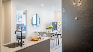 A modern kitchen with a central island, a dining area with a glass table, and a dark wall with the number 42. - 42 City Gate - 24-hour Gym Access Included! Sleeps 4 guests in 2 bedrooms (York)