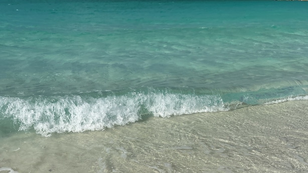 A beach with clear turquoise water and gentle waves.