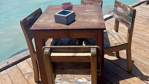 A wooden deck with a table and chairs overlooking turquoise waters.