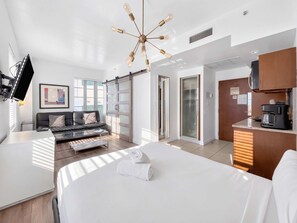 A hotel room with a bed, a sofa, a coffee machine, a TV, and a sliding door closet.