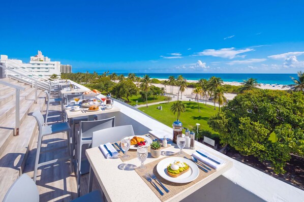 A rooftop dining area with a view of the beach and ocean.