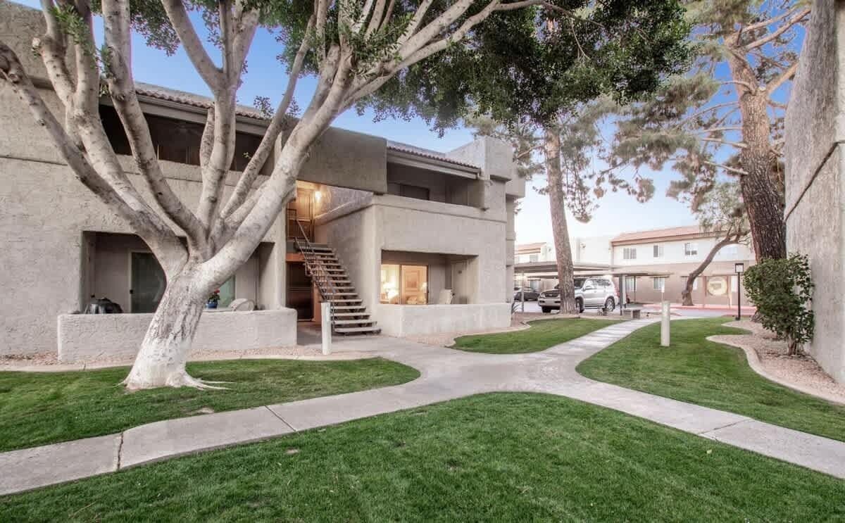 A modern building with a concrete facade, a central staircase, and a well-maintained lawn.