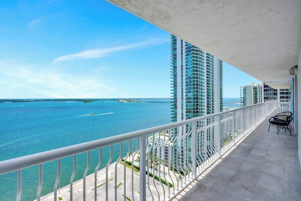 A balcony with a view of the ocean and tall buildings.
