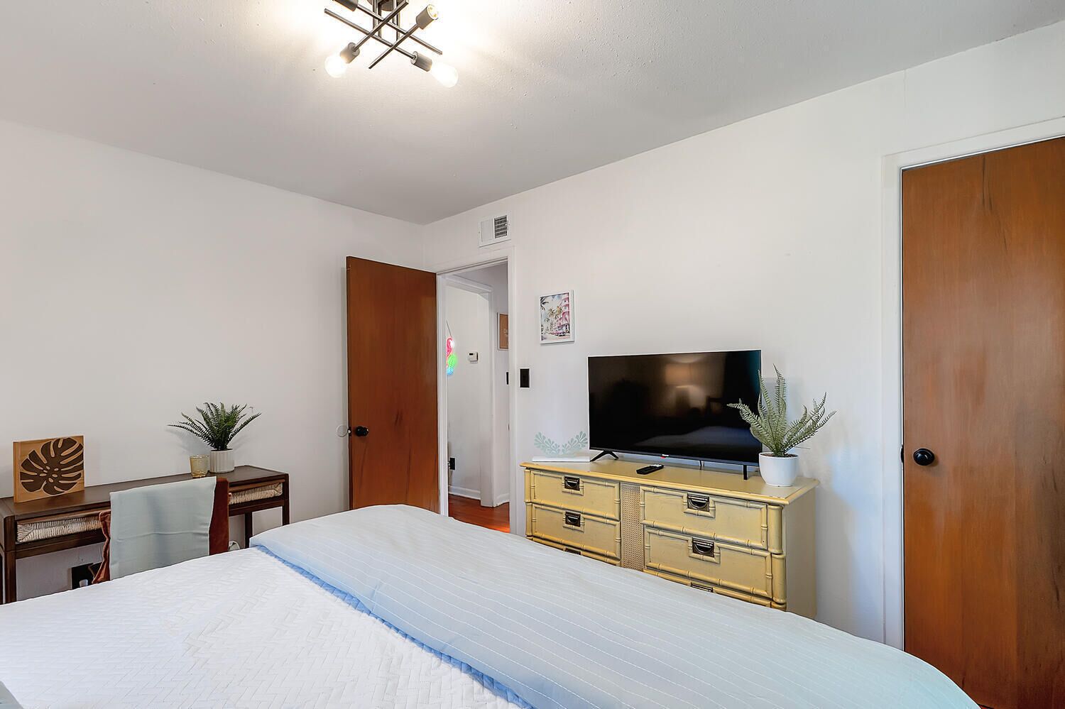 A bedroom with a bed, a TV, a dresser, and a door.