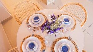 A round dining table with four chairs, each with a woven placemat and a blue and white plate set. A vase with purple flowers is placed in the center. - Relax in front of the sea (Cartagena de Indias)