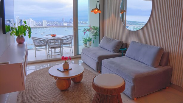 A modern living room with a grey sofa, a round coffee table, a TV, and a balcony with a view of the city and water. - Relax in front of the sea (Cartagena de Indias)
