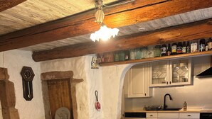 Ein gemütlicher Essbereich mit Holztisch und roten Stühlen, eine Küche mit weißen Schränken und ein Steinboden.