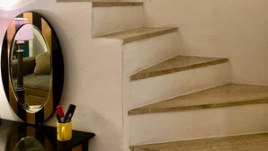 Una escalera con barandilla de madera, un espejo y una pequeña mesa con bolígrafos.