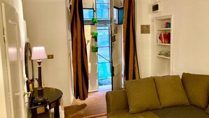 Una sala de estar con sofá, lámpara y cortinas.