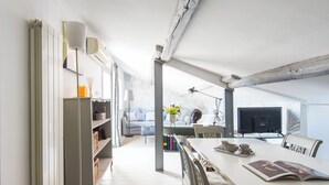 A modern, well-lit dining area with a white table, chairs, and a bookshelf filled with books and decorative items. - British Embassy Terrace Apartment (Rome)