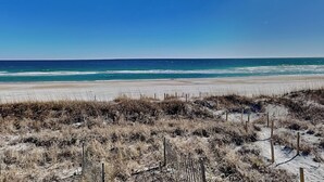 Una playa con cielo despejado y una valla en primer plano.