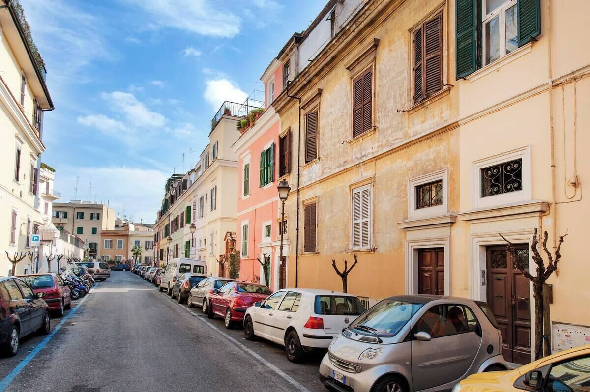 Una strada fiancheggiata da auto parcheggiate e palazzi con architettura tradizionale.